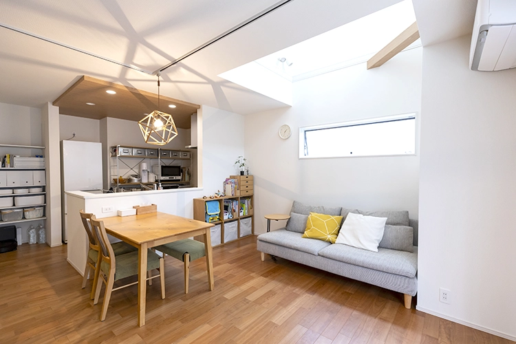 玄関を抜けると、白い壁紙と明るい色合いの木材が調和したリビングが広がります